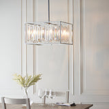 Aldbourne 6 Light Pendant in chrome with bevelled crystal glass rods in a rectangular frame, hanging above a dining table in a panelled room.