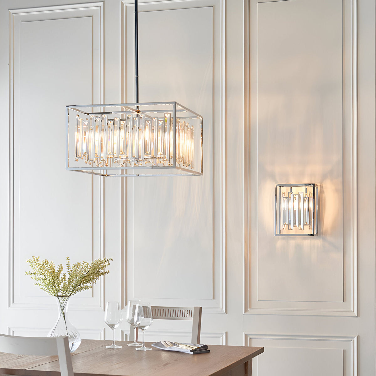 Aldbourne 6 Light Pendant in chrome with bevelled crystal glass, shown above a dining table beside a matching wall light in a panelled room.