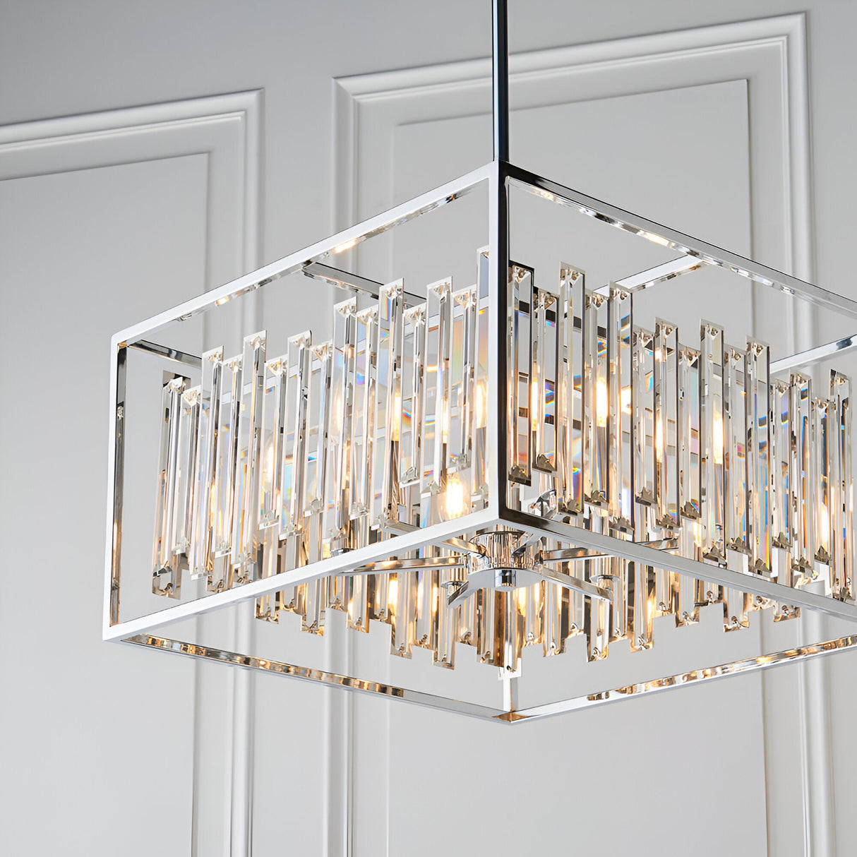 Aldbourne 6 Light Pendant in polished chrome with a square frame and bevelled crystal glass rods, shown against a panelled white wall.