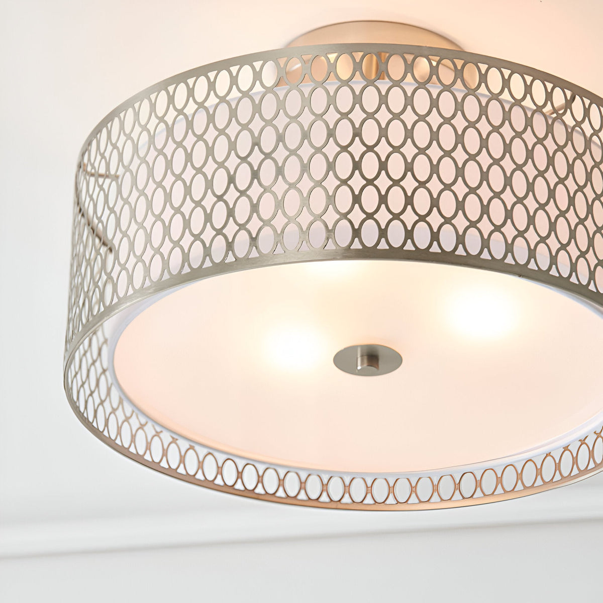 Endon Rosaline 3 light flush ceiling light in nickel with perforated circle drum shade and frosted glass diffuser, illuminated against a white ceiling.