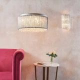 Endon Isadora 2 light wall light in polished chrome with twisted rods and K9 crystals, shown lit beside a pendant above a pink armchair and side table.
