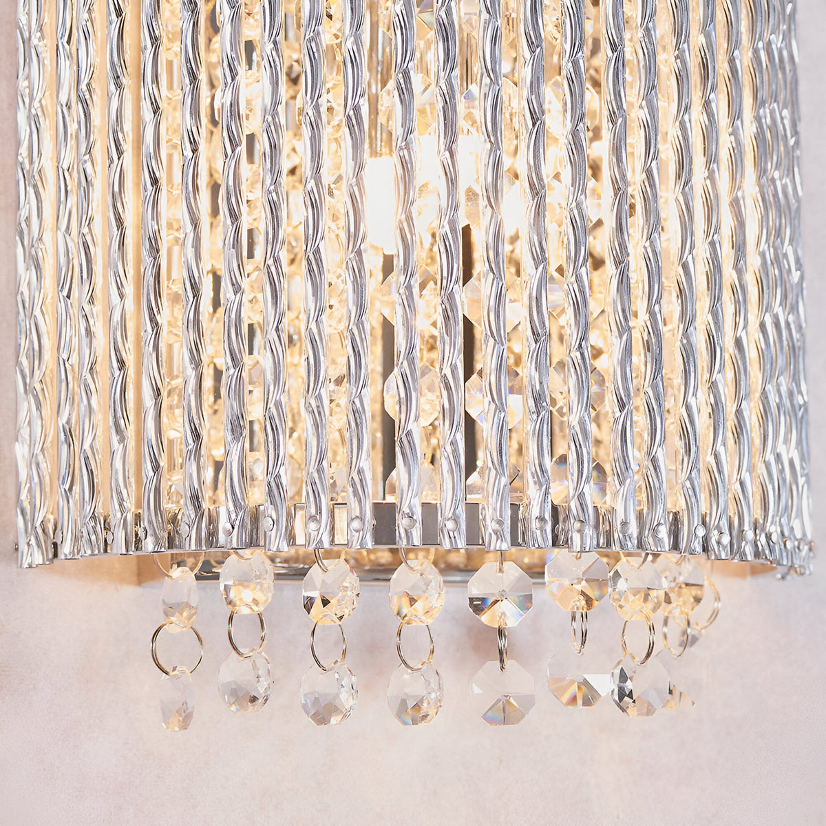 Close-up of illuminated Endon Isadora 2 light wall light showing twisted polished chrome rods and K9 clear crystal droplets along the base.