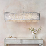 Endon Isadora 8 light linear pendant in polished chrome with twisted rods and clear crystal droplets, hung above a mirrored console with white flowers.