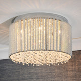 Isadora 10 Light Crystal Flush Ceiling Light in clear, drum-shaped with crystal rods and hanging droplets, shown illuminated on a white ceiling.