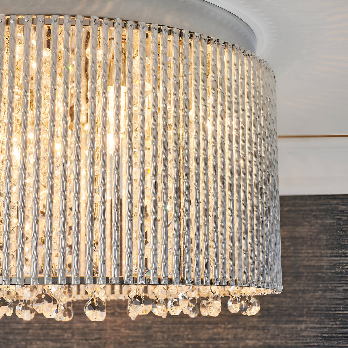 Close-up of the Isadora 10 Light Crystal Flush Ceiling Light in clear, showing ridged chrome strips and hanging crystal droplets with visible G9 bulbs lit.