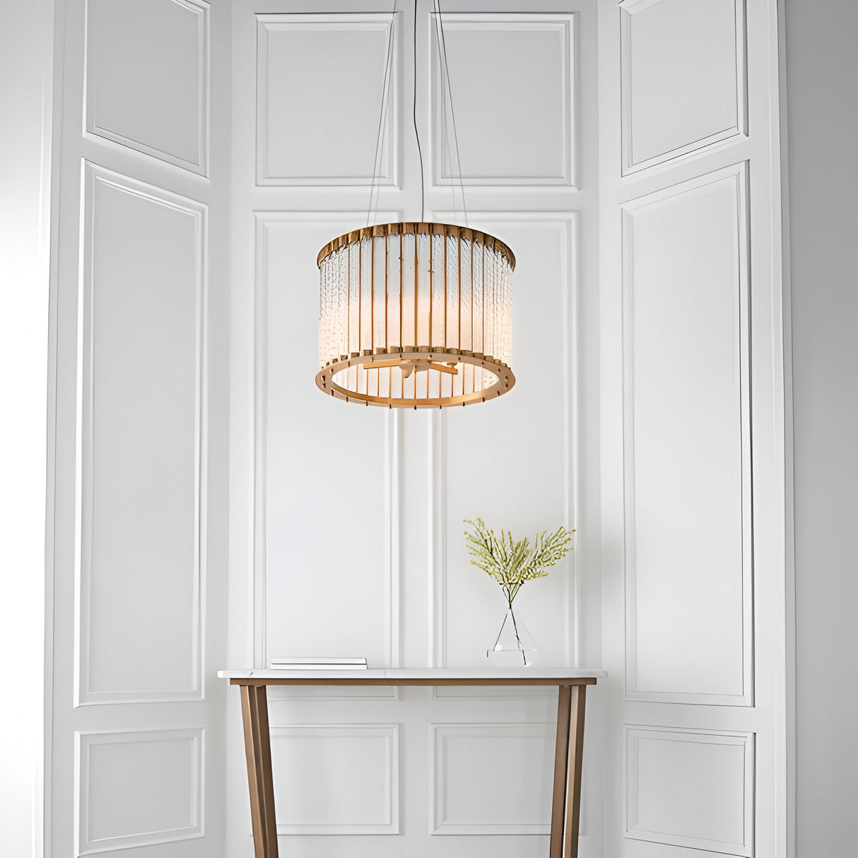Cliffdale 6 Light Pendant in matt gold, drum-shaped frame with twisted glass rods, hanging above a console table against white panelled wall.