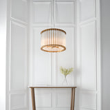 Cliffdale 6 Light Pendant in matt gold, drum-shaped frame with twisted glass rods, hanging above a console table against white panelled wall.