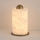 Aurelior Small LED table lamp with ribbed cylindrical alabaster body glowing warm white, topped by a brass dome cap and set on a slim brass base disc, shown against a plain light background.