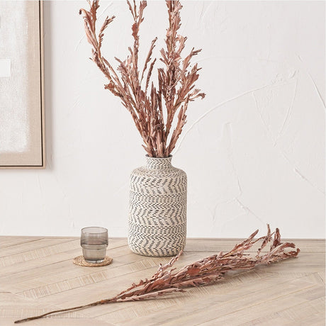 Mulberry Brown Autumn Leaf artificial flower stems, pack of 6, displayed in a patterned white and black vase with one stem laid on a wooden floor beside it.