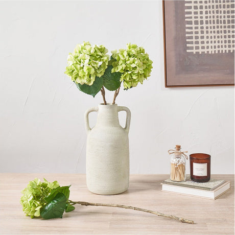 Artificial green hydrangea stems, part of a pack of 6, displayed in a textured cream vase with handles alongside a single loose stem on a wooden surface.
