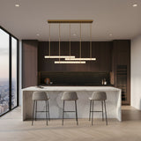 Niori Selvara 3 Light Horizontal Alabaster Linear Pendant in brushed brass above a white marble kitchen island with three grey barstools.