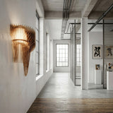 A modern industrial-style hallway featuring large windows, white brick walls, wooden floors, abstract art, and the Aeris 3 Light Wall Light - Gold as a sculptural fixture providing ambient lighting.