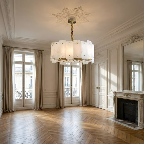Elegant empty room with ornate white walls, tall windows with beige curtains, herringbone wood floors, a large mirror, and a detailed fireplace. The Caldrin 6 Light Tiered Panel Alabaster Chandelier in soft white & brass brightens the space.