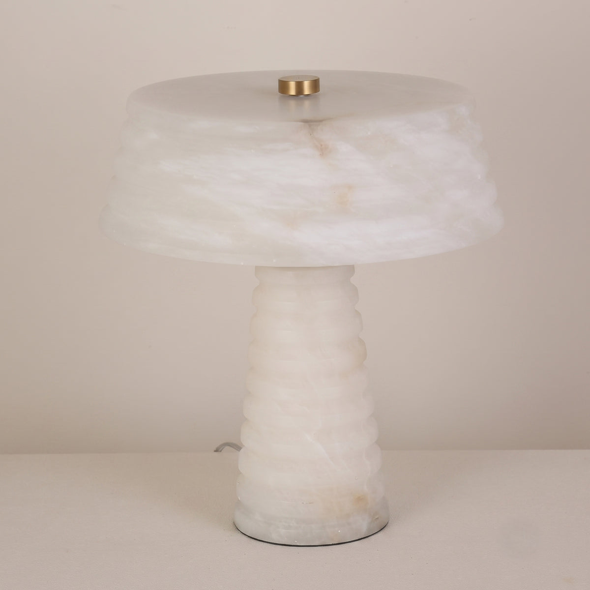 Orivon 3 Light Sculpted Alabaster Table Lamp in soft white, with a ribbed tapered base and banded drum-form shade joined by a brass finial, shown on a plain light background.