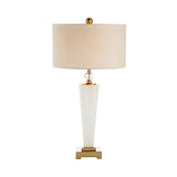 The Aureum 1 Light Refined Silhouette Marble Table Lamp features a tall white marble base with brass accents and a round beige fabric shade, displayed against a plain white background.
