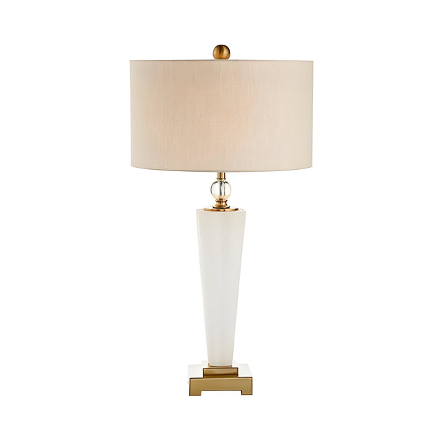 The Orvani 1 Light Refined Silhouette Marble Table Lamp features a white tapered base, beige drum shade, brass accents, and a square gold platform for a modern, elegant look.