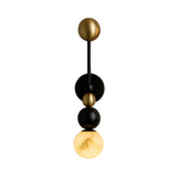 The Zeal 1 Light Vertical Orb Alabaster Wall Light features soft white, black, and brass spheres in a modern vertical design, with the bottom orb casting a warm glow.