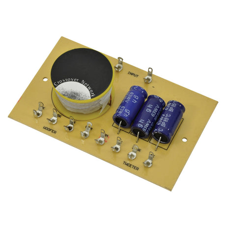 A close-up of the QTX 2-Way Crossover circuit board, showcasing a large capacitor labeled "Crossover Network," along with three cylindrical capacitors and several resistors. Designed for sound reproduction, this component features frequency separation, with clearly marked input and output points for 2-way crossovers in an 8 Ohm speaker system capable of handling up to 100W at frequencies of 2/2.5/4kHz.