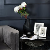 Libra Interiors Polished Nickel 10x15cm Photo Frames displayed on a black glass side table beside a black vase of white peonies, a cup and magazines.