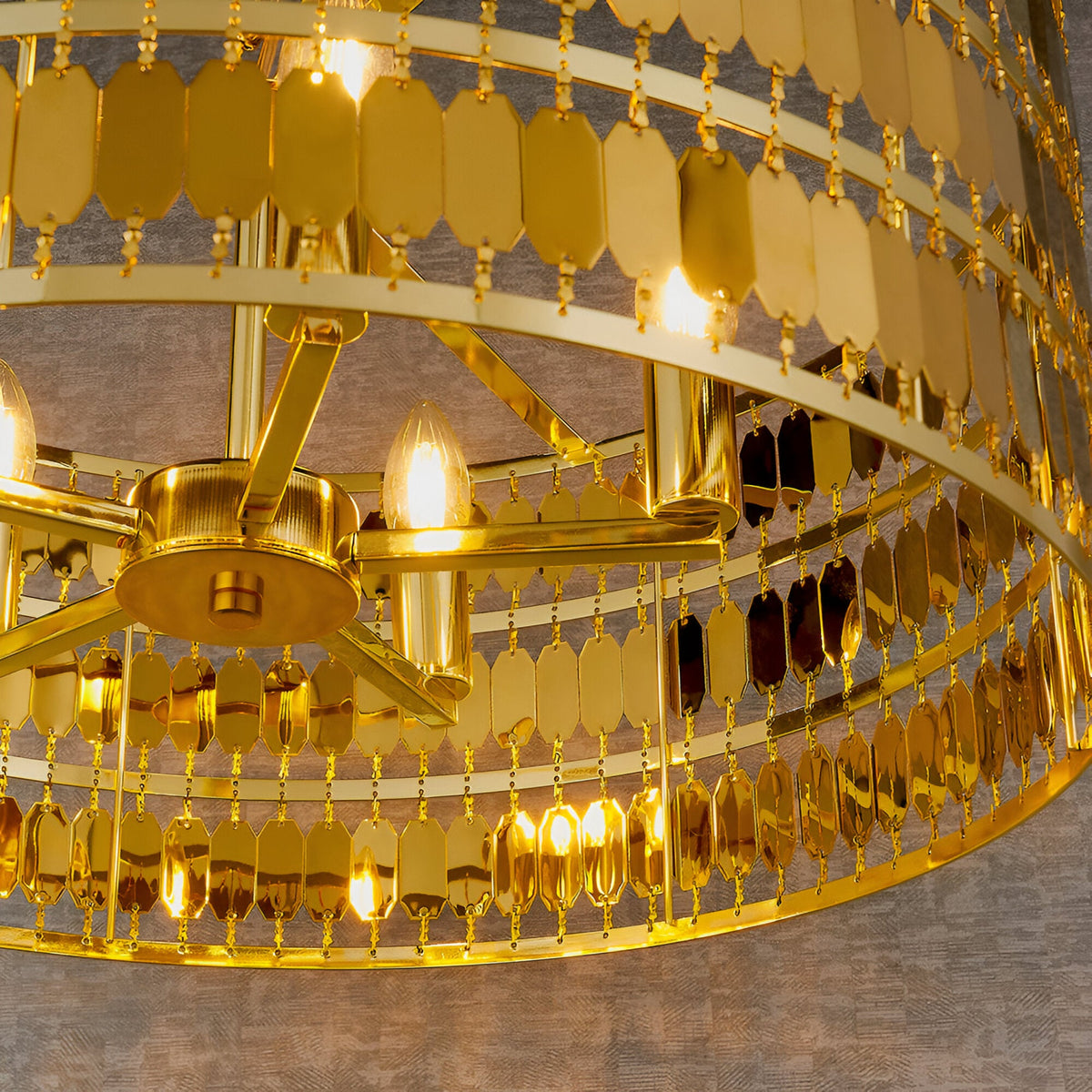 Close-up of the Brackhurst 5 Light Pendant in gold, showing layered hexagonal metal plates and candle-style bulbs on a central gold frame.