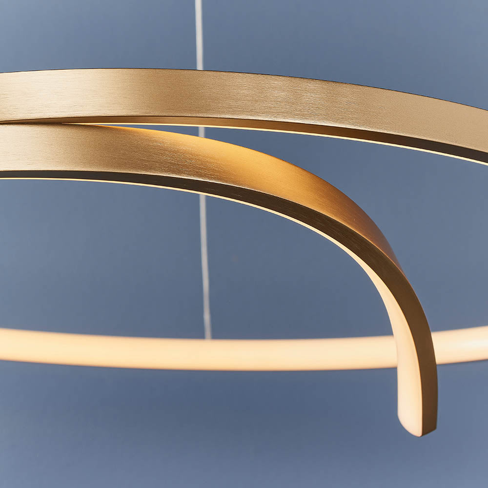 Close-up of the Endon Chartmont pendant showing its slim curved ring in matt brushed gold with a frosted diffuser, set against a blue backdrop.