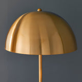 Endon Castford floor lamp close-up showing antique brass domed shade with finial and slim brass stem against a dark grey background.