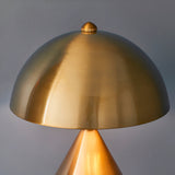 Castford Table Lamp in antique brass with a dome-shaped metal shade and ribbed finial detail, close-up view against a plain grey background.