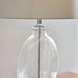 Close-up of the Endon Bramleigh table lamp's clear glass ellipsoid base with polished nickel fitting and white tapered shade above.