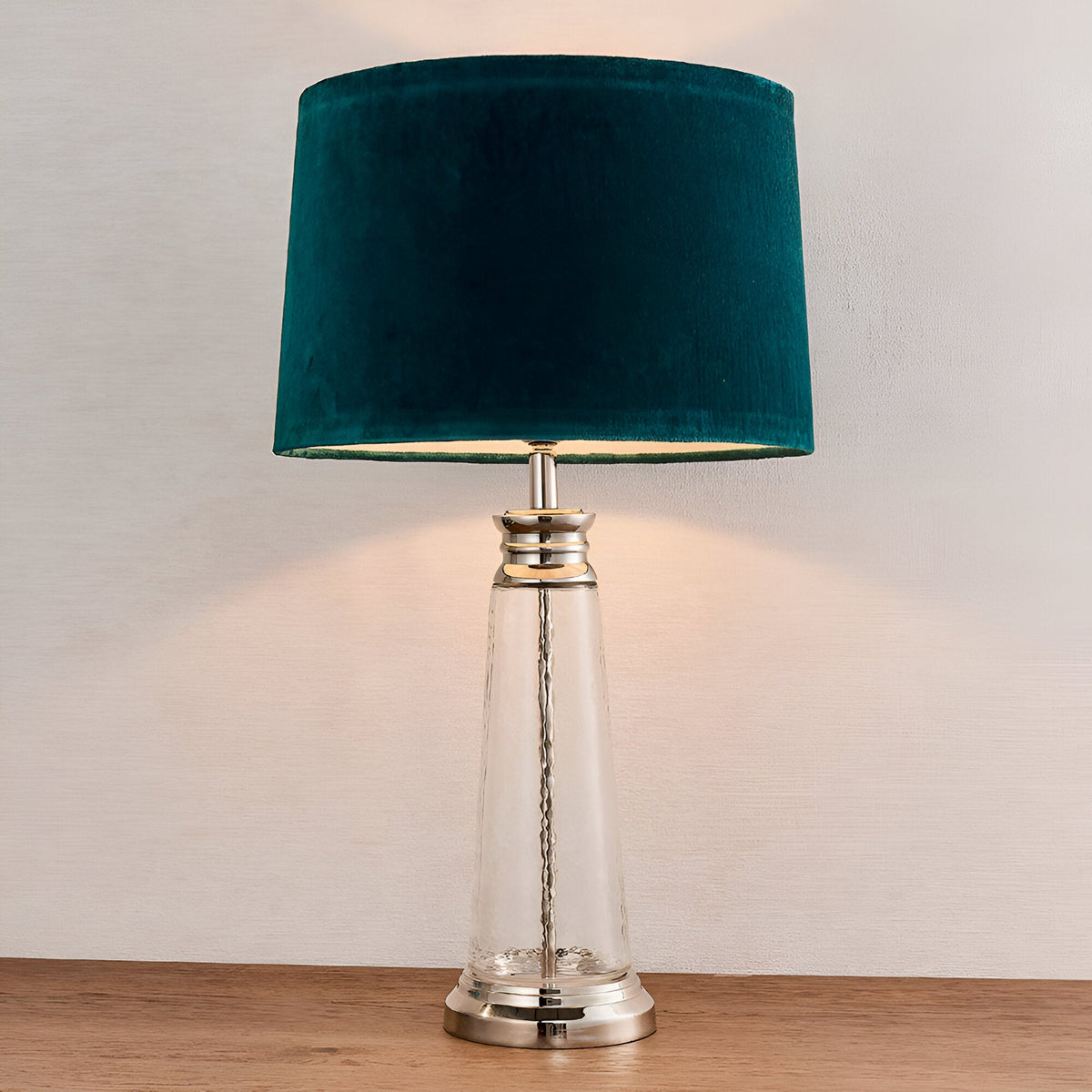 Endon Danehurst table lamp with clear hammered glass base, nickel metalwork and teal velvet tapered shade on a wooden surface.
