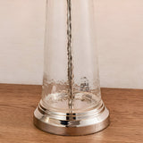 Close-up of the Endon Danehurst table lamp base showing clear hammered glass and a tiered bright nickel plated foot on a wooden surface.