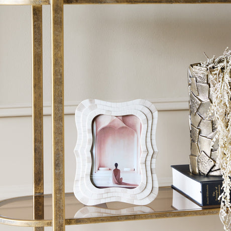 Libra Interiors Mosaic Tiled Resin Photo Frame in ivory with wave-shaped scalloped border, displayed on a mirrored gold shelf beside a book and vase.