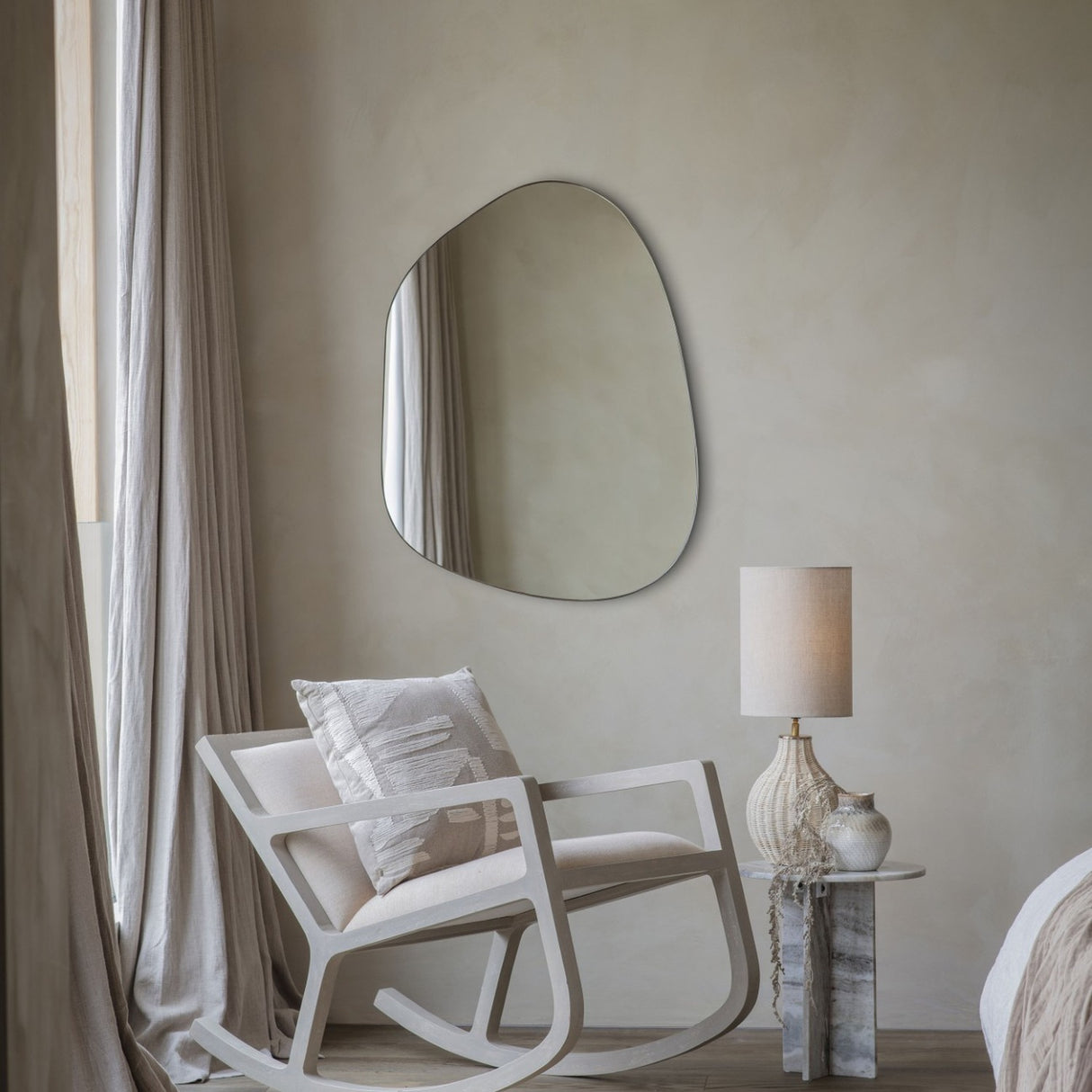 Libra Interiors Textured Cotton 50cm square cushion in natural beige with cream stitched motif, on a white rocking chair beside a shaped wall mirror and lamp.