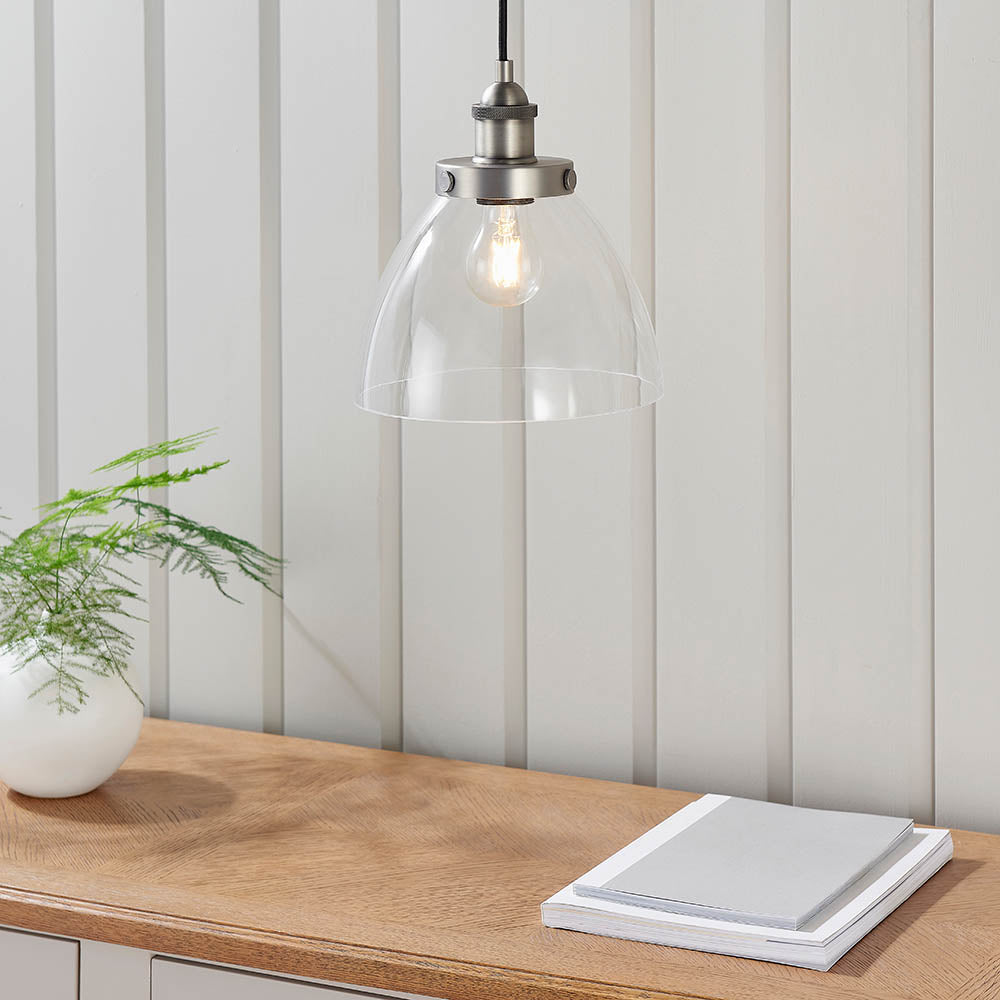 Wentworth Pendant Light in Silver with clear glass dome shade and exposed filament bulb, hung above a wooden console in a light-panelled room.