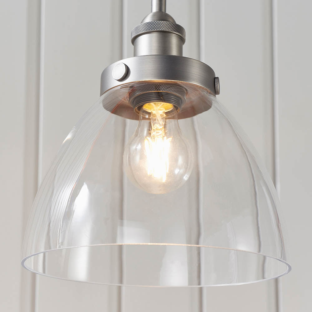Wentworth Pendant Light in silver with a clear glass dome shade, knurled metal lamp holder, and exposed E27 filament bulb, shown against a light panelled wall.