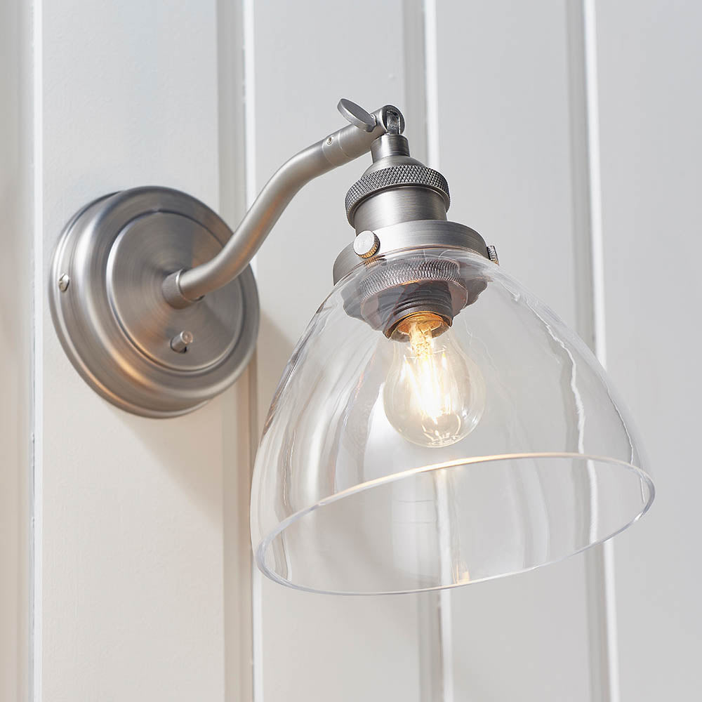 Wentworth Wall Light in silver, industrial-style fitting with adjustable knuckle joint, knurled holder and clear glass dome shade, mounted on white wall.