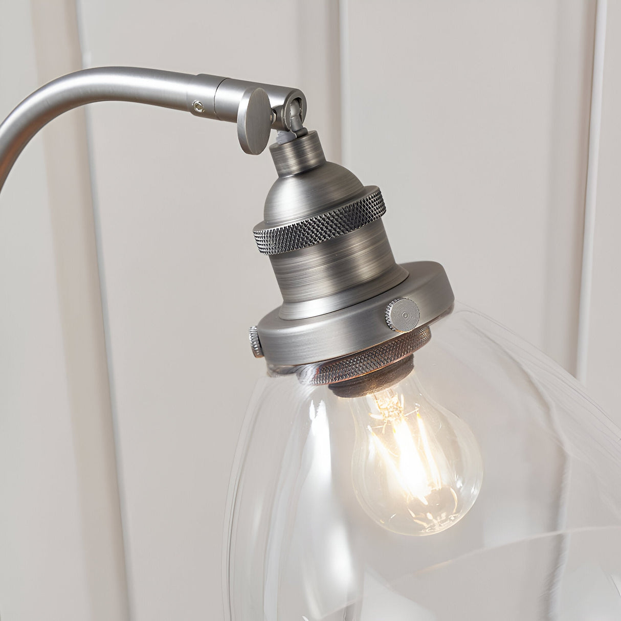 Close-up of the Endon Wentworth table lamp's brushed silver head with knurled holder, adjustable knuckle, clear glass shade and filament bulb.