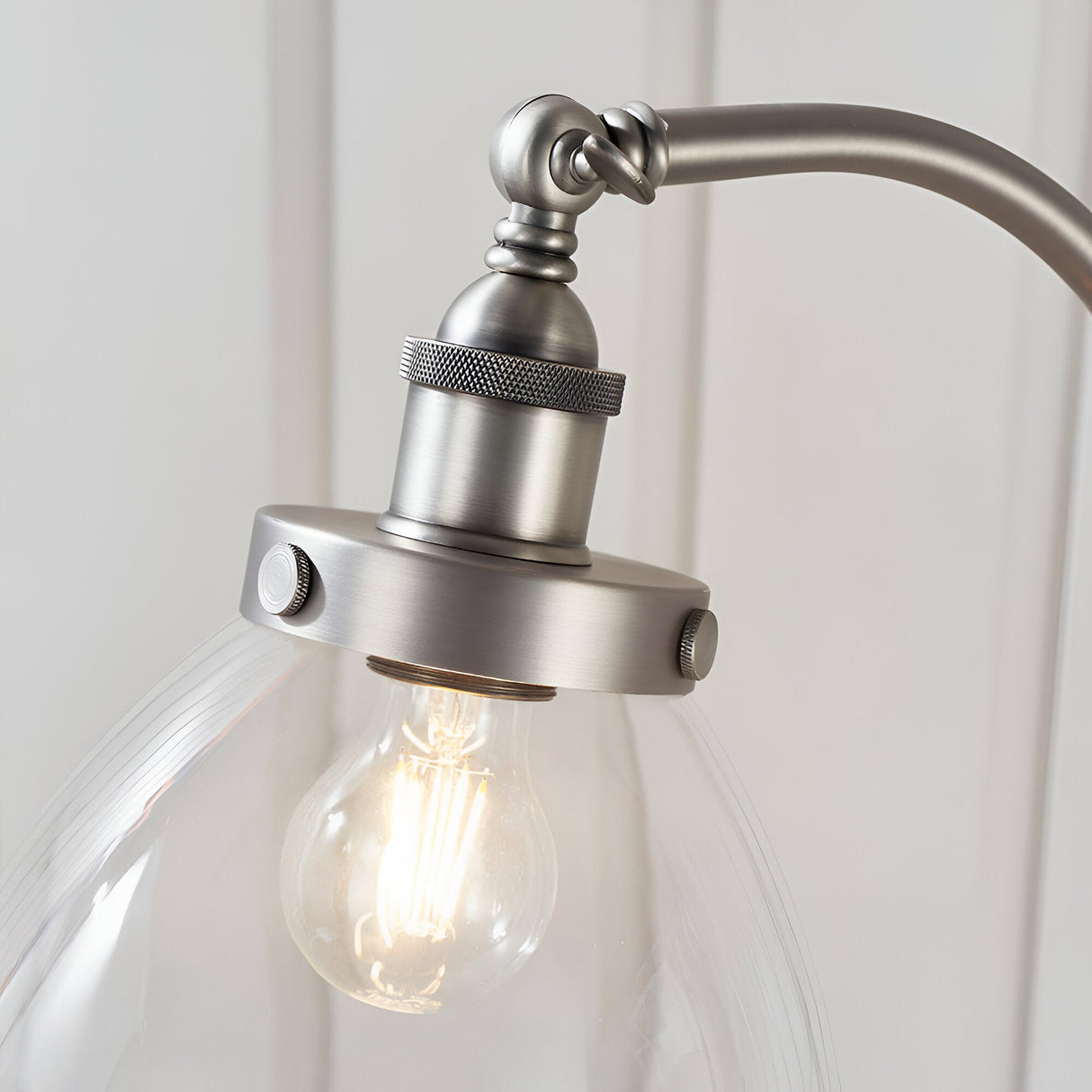 Close-up of Endon Wentworth floor lamp in brushed silver, showing the knurled E27 lamp holder, adjustable knuckle and clear glass shade with filament bulb.