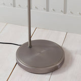 Close-up of the Endon Wentworth floor lamp's round brushed silver base and stem on pale wood flooring, with black fabric flex trailing behind.