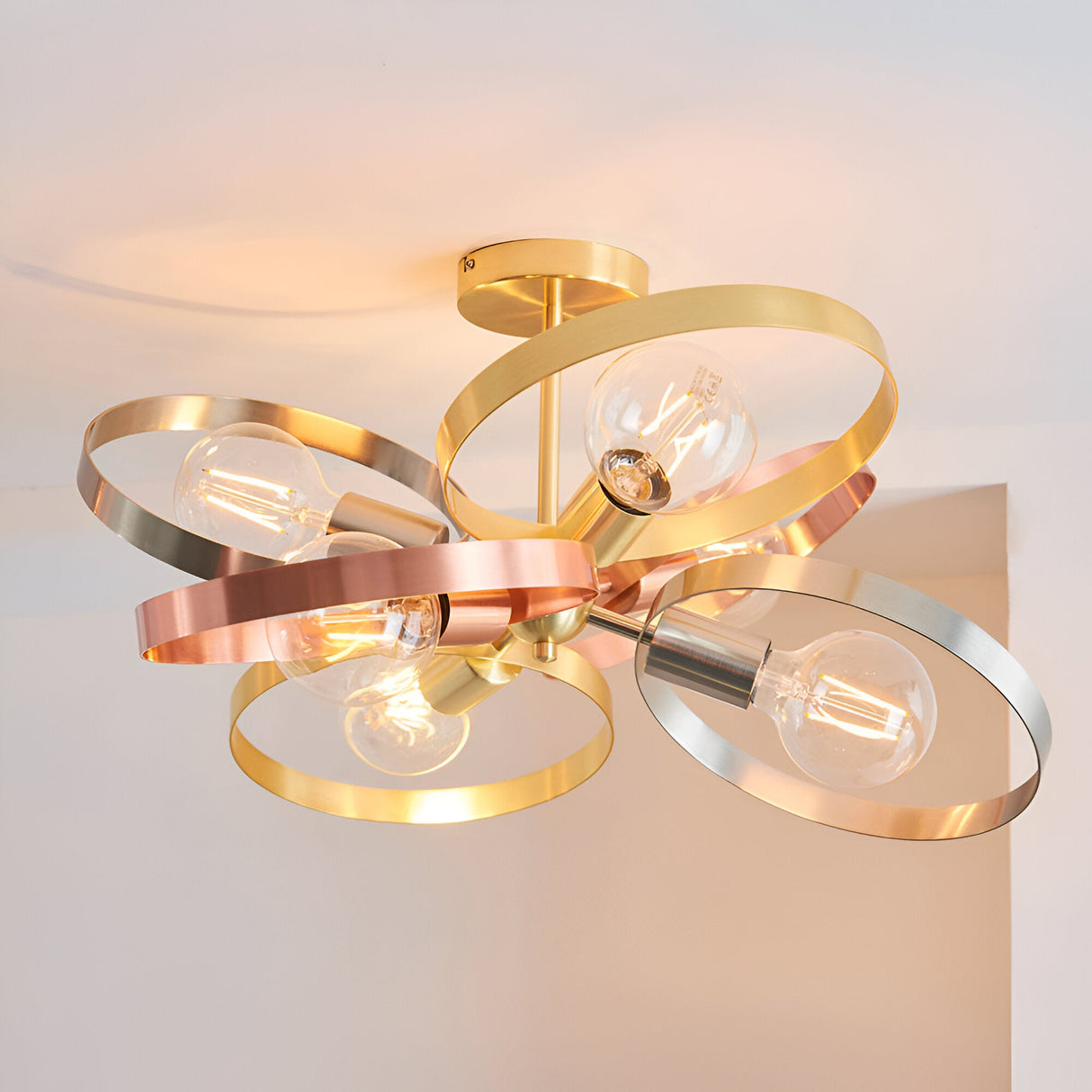 Endon Brenmere 6 light semi-flush pendant with brushed brass, copper and nickel open hoops and exposed E27 filament bulbs, shown against a pale ceiling.