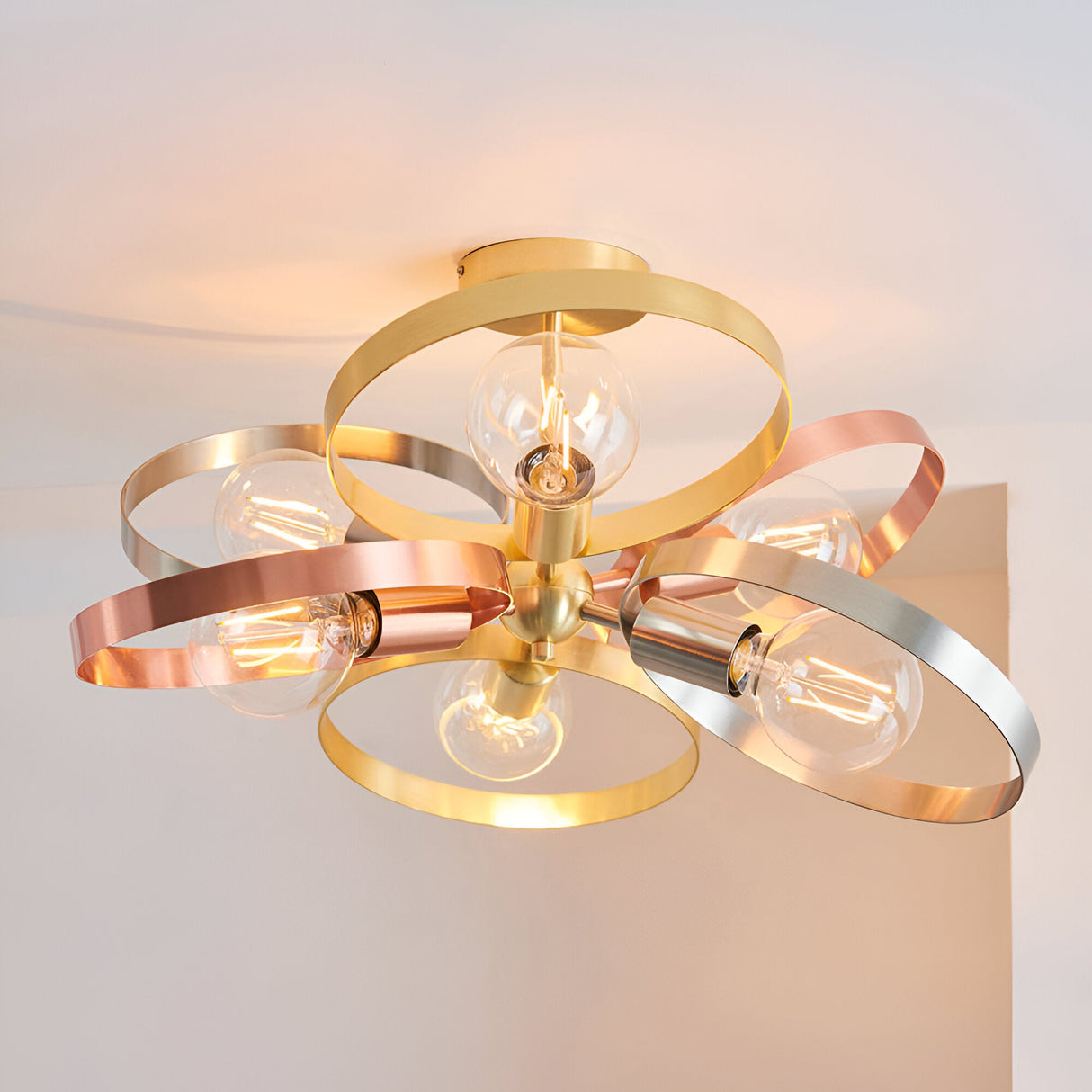 Endon Brenmere 6 light pendant with brushed brass, copper and nickel open hoops and exposed filament bulbs, mounted to a white ceiling.