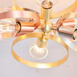Close-up of the Endon Brenmere 6 light pendant showing its brushed brass central hub with copper, nickel and brass hoops and exposed E27 filament bulbs.