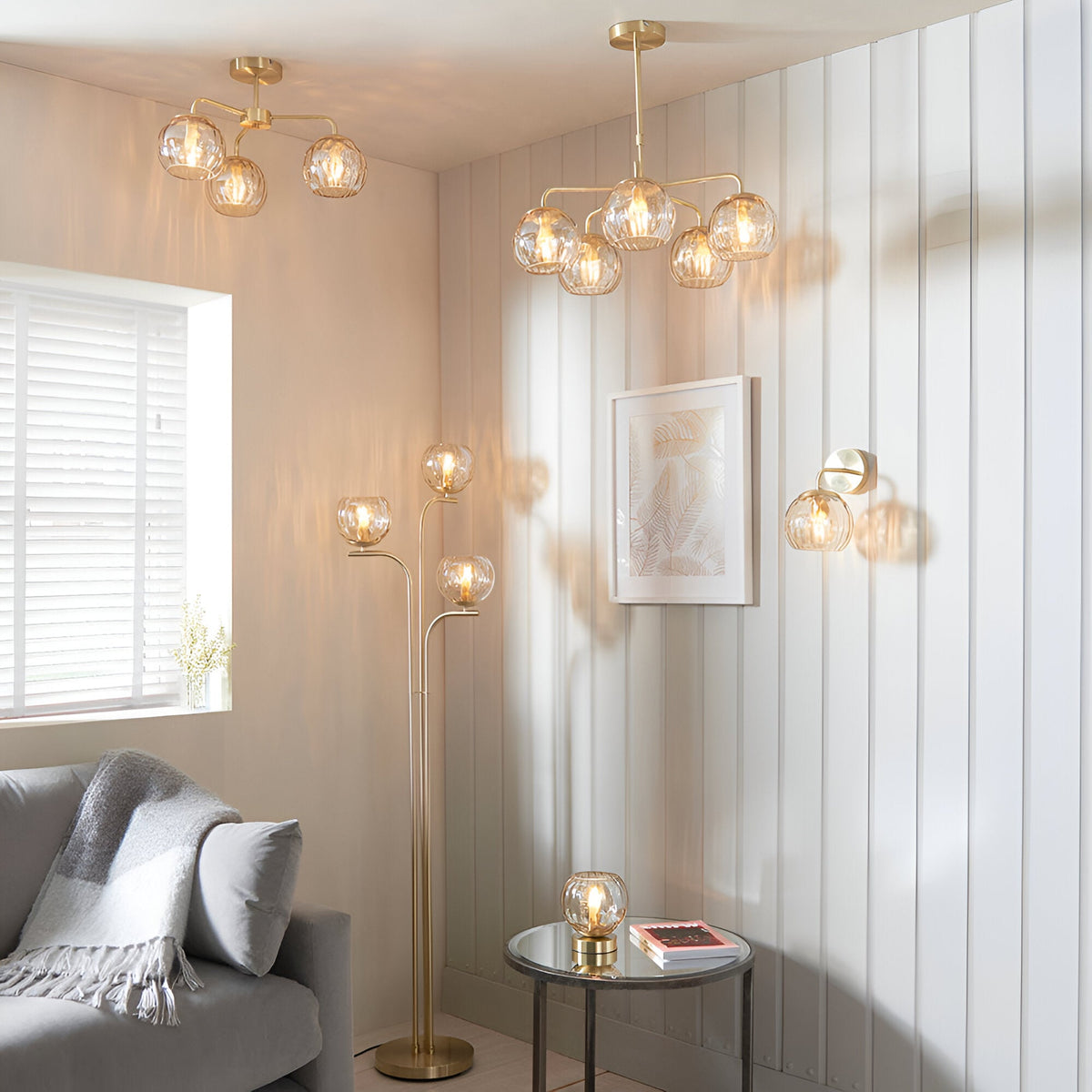 Endon Everly 3 light semi-flush ceiling light in gold with glass globe shades, shown in a living room alongside matching floor, table, wall and pendant lights.