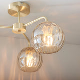 Endon Everly 3 light semi-flush ceiling light in gold, with dimpled glass globe shades on curved brass arms mounted to a circular ceiling plate.