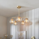 Endon Draycott 5 light pendant with dimpled champagne glass globe shades on a satin brass frame, installed in a bright neutral interior.