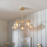 Endon Draycott 5 light pendant with champagne dimpled glass globes on a satin brass frame, installed above a framed print in a modern room.