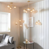 Endon Draycott pendant, ceiling light and floor lamp in brass with dimpled champagne glass shades, styled in a living room with grey sofa and side table.