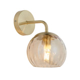 Endon Draycott wall light with a single champagne lustre dimpled glass globe shade on a satin brass arm and round backplate, on a white background.