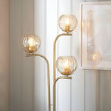 Endon Draycott 3 light floor lamp with champagne dimpled glass globe shades on a satin brass stem, styled beside sheer curtains and a framed print.