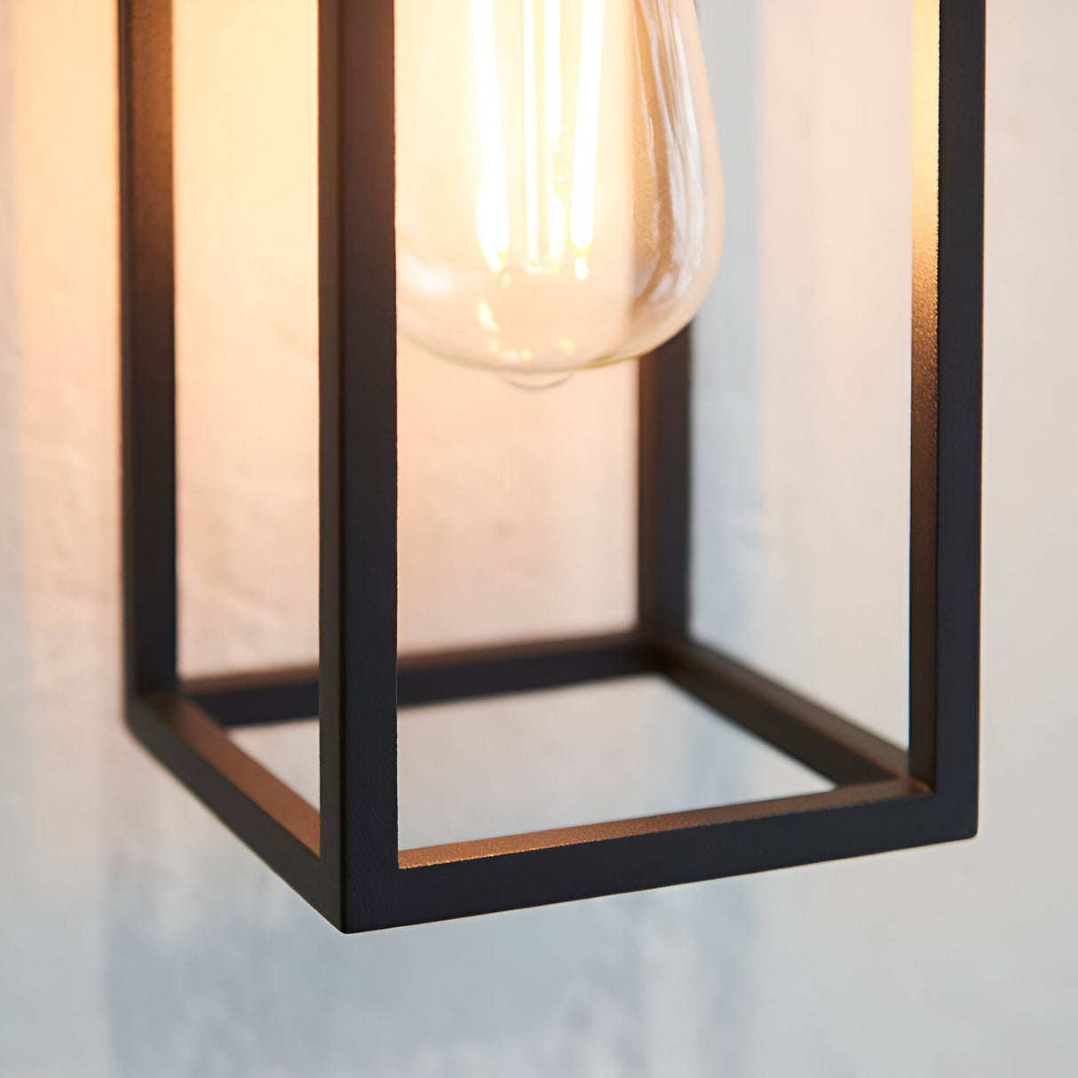 Close-up of the Brenford Outdoor Wall Light in black, showing its open aluminium cage frame and exposed filament bulb, IP44 rated.