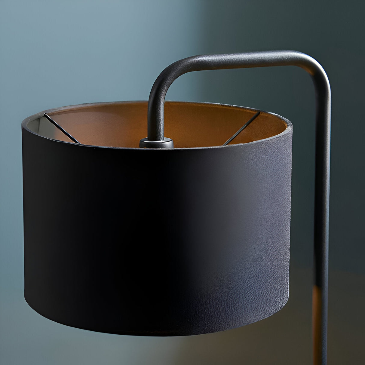Caldfield Table Lamp in satin black, close-up of the cylindrical fabric shade with copper-toned interior and curved metal arm on a bedside stem.